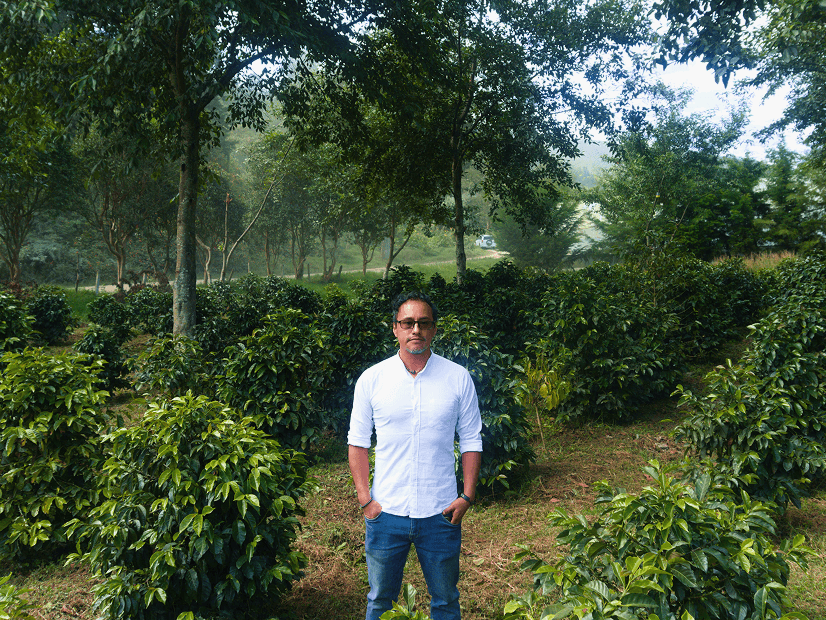 Johny Granja, investigador del proyecto PROISCA, de pie con los brazos cruzados en las plantaciones de café de la UNL